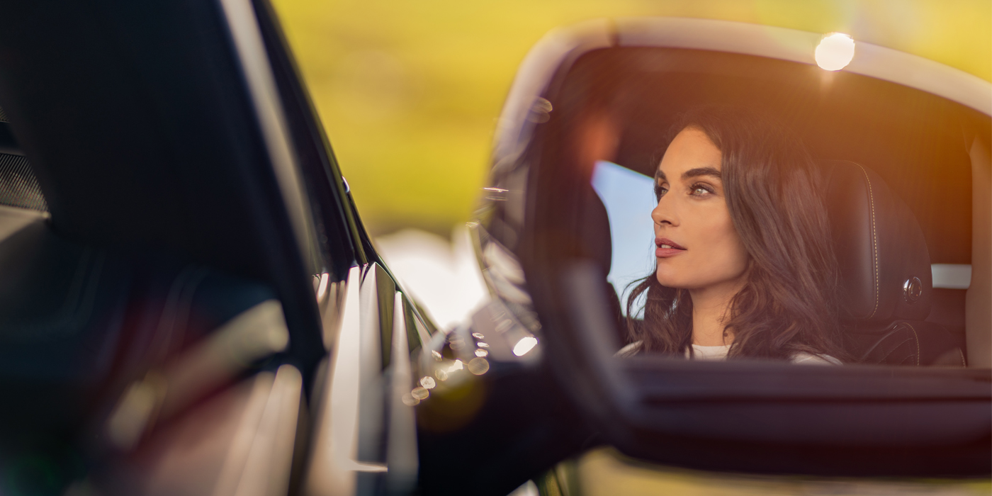 Bentley Rotterdam profile of dark haired woman's face in mirror of Bentley car in sunlight
