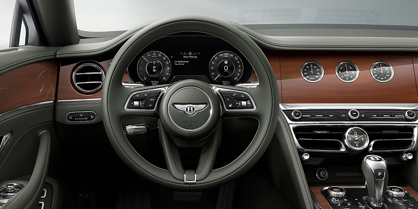 Bentley Rotterdam New Bentley Flying Spur sedan front cabin in Cumbrian Green hide and Crown Cut walnut veneer showing steering wheel and Rotating Display with three clocks on face
