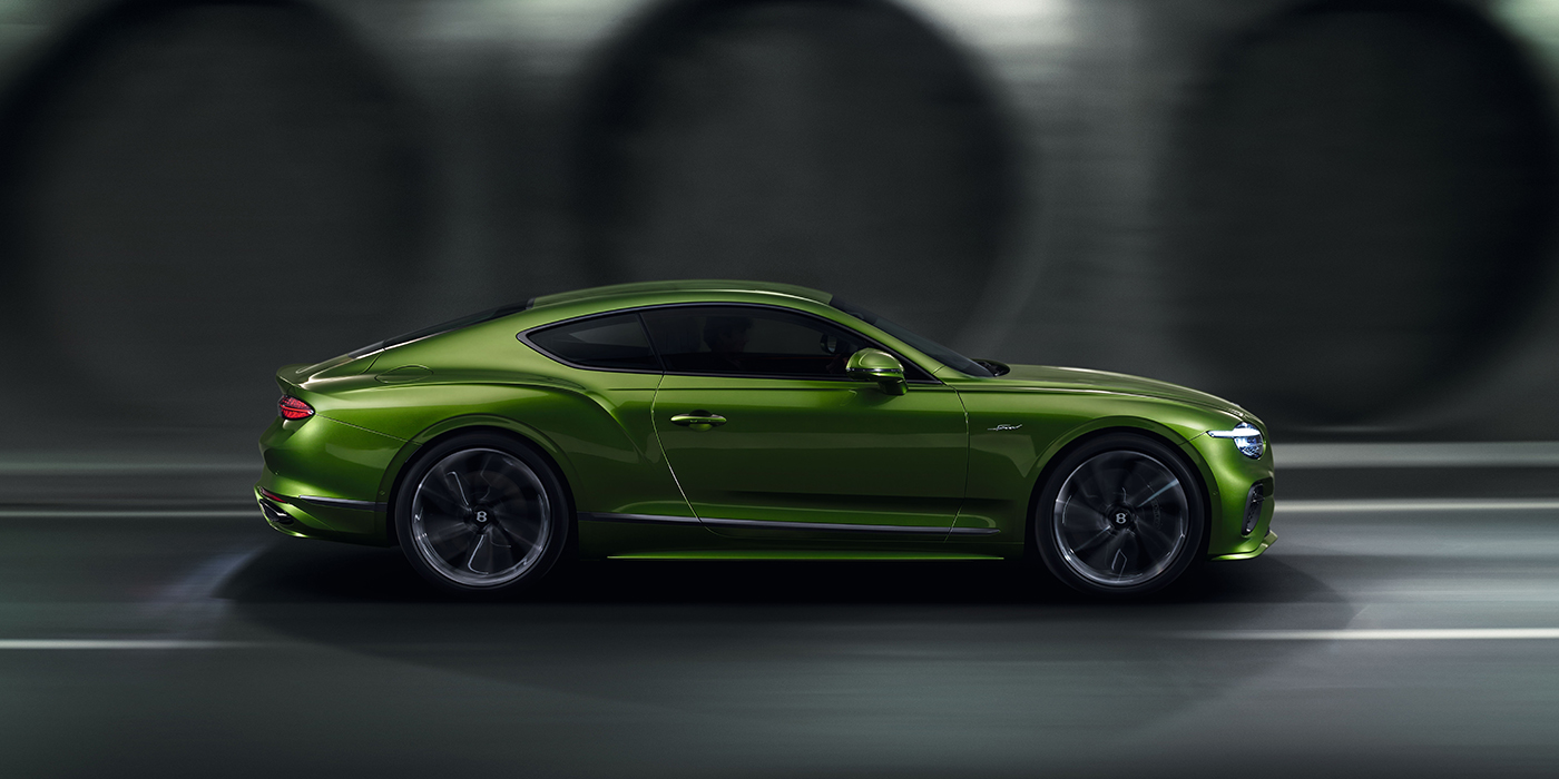 Bentley Rotterdam Bentley Continental GT coupe in Tourmaline Green paint driving in profile on a dark road